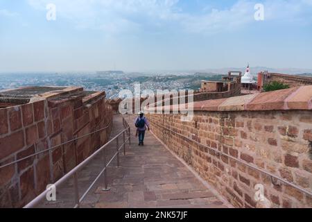 Indian modern female solo traveller walking past stone made way to Chamunda Mataji temple at Mehrangarh fort,Jodhpur,Rajasthan, India. Famous temple. Stock Photo