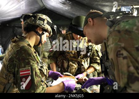 Lativian Tactical Savers, assigned to the Latvian Land Forces, alongside a U.S. Army Soldier assigned to Charlie Company, 237th Support Battalion, treat a simulated casualty during a medical triage exercise at Camp Grayling, Michigan, Aug. 11, 2022. The exercise was conducted as part of Operation Northern Strike, the annual training event for over 2,000 Ohio and Michigan National Guard Soldiers who worked side-by-side with allies from Latvia, the United Kingdom, and others to maintain cohesion and battlefield readiness amongst units and allies. Stock Photo