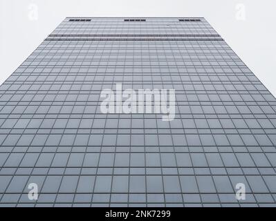 bottom view of flat glass wall of skyscraper on overcast day Stock Photo