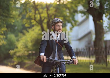 Successful male executive wearing smart casual commuting to work in early morning. Front view of smiling man in elegant suit looking ahead, while ridi Stock Photo