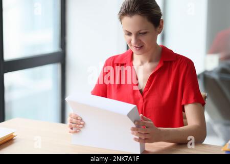 A woman in office holds a stack of white sheets of paper Stock Photo
