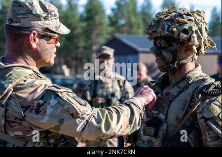 Command Sgt. Maj. Charles Walker, senior enlisted advisor of the 2nd BCT, 101st Airborne, promotes Sgt. 1st Class Daniel McFadden, assigned to 1st Battalion, 26th Infantry Regiment, 2nd Brigade Combat Team, 101st Airborne Division (Air Assault) following a combined arms live fire exercise between U.S. and Finnish forces, Rovaniemi, Finland, Aug. 11, 2022. Stock Photo
