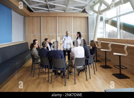 Business trainers old man and young woman conduct training in office for group of people. Stock Photo