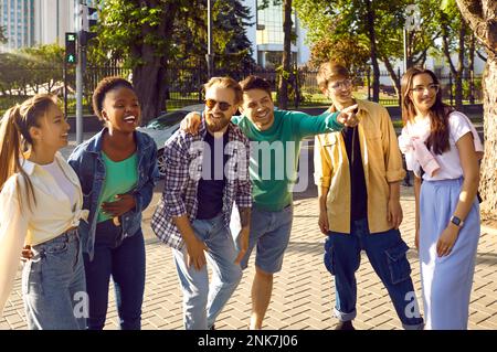 Group of cheerful tourist friends are walking together on streets of new city and exploring. Stock Photo