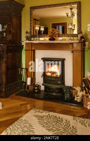 Cosy winter living room fireplace, with wood burning stove, UK home interior with antique furnishings. Stock Photo