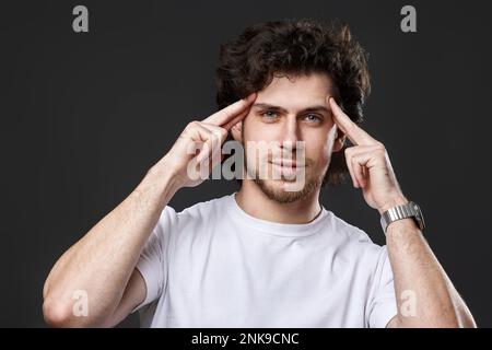 young bearded man showing victory gesture holding fists raising hands up on gray background Stock Photo