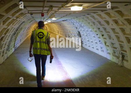 London, England, UK - Guide leads tour by torch light in tunnel of Clapham South Deep-Level Shelter built in World War II as an air-raid shelter Stock Photo