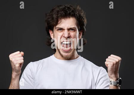 very excited young man showing victory gesture Stock Photo