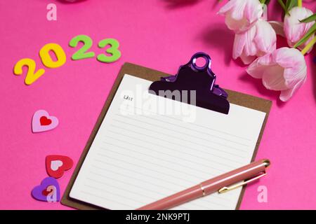 Composition with blank, 2023 and beautiful tulip flowers on pink background Stock Photo