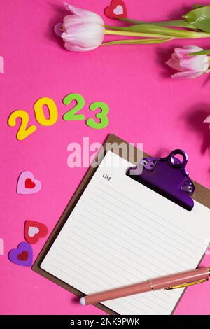 Composition with blank, 2023 and beautiful tulip flowers on pink background Stock Photo