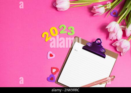 Composition with blank, 2023 and beautiful tulip flowers on pink background Stock Photo