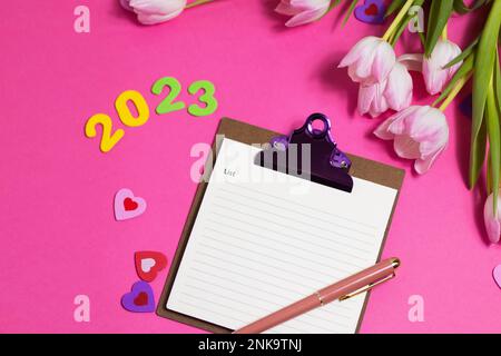 Composition with blank, 2023 and beautiful tulip flowers on pink background Stock Photo