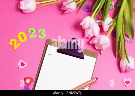 Composition with blank, 2023 and beautiful tulip flowers on pink background Stock Photo