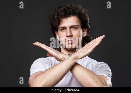 young bearded man showing stop gesture on dark gray background Stock Photo