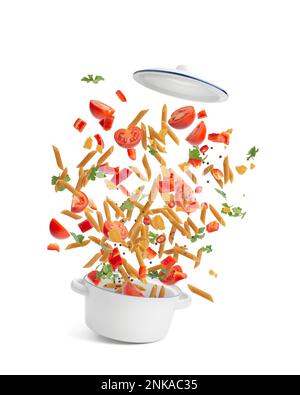 White saucepan with pasta and vegetables, tomatoes and herbs flying in the air on a white isolated background. Levitation. Stock Photo
