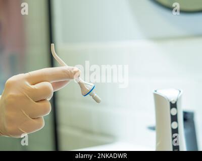 Dentist's hand showing how to use domestic dental water flosser for a deep cleaning at home Stock Photo