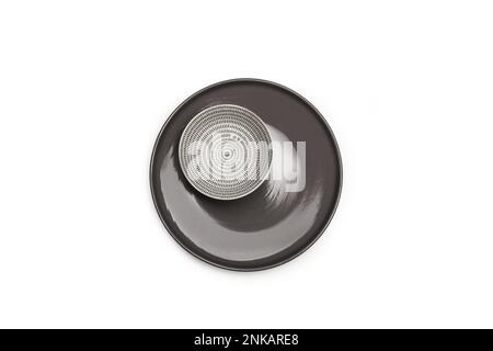 A white and black ceramic bowl on a gray plate on a white background with copy space in a top view Stock Photo