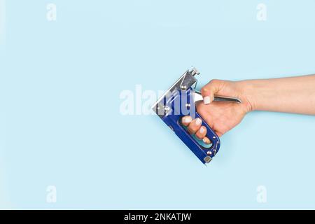 Woman hand holding a blue stapler gun on a white background with copy space Stock Photo