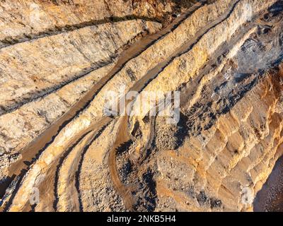 Stone quarry with small excavator aerial drone view in winter sun Stock Photo