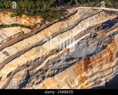 Stone quarry with small excavator aerial drone view in winter sun Stock Photo