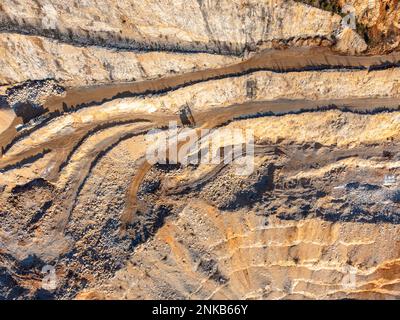 Stone quarry with small excavator aerial drone view in winter sun Stock Photo