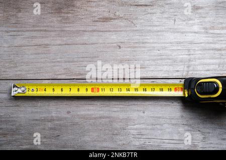 Measuring tape stretched 21 cm on a wooden background. Close-up. Selective focus. Stock Photo