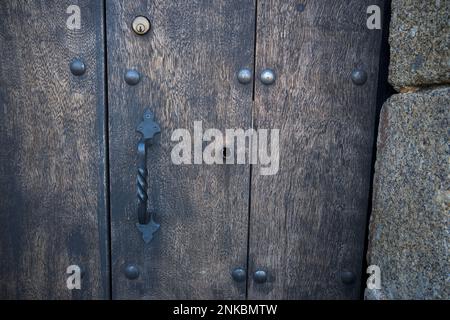 Old and modern lock on old dark door with iron handle in horizontal Stock Photo