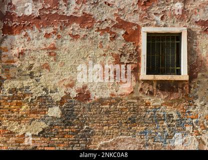 White window on old house wall Cracks in concrete visible red bricks in Venice, Italy. Stock Photo