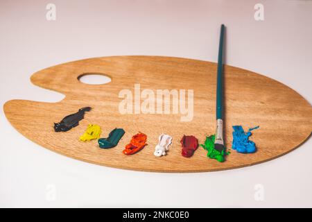 Wooden palette with colored oil paints and brushes isolated on a white background Stock Photo