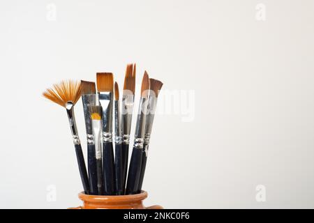 Earthenware jar with brushes isolated on a white background Stock Photo