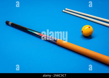 Cue sticks and a yellow ball on a billiard table Stock Photo