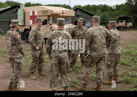 U.S. Army Col. Gunnar Kiersey, Deputy Surgeon, Army National Guard Bureau, and Chief Warrant Officer 5 Patrick Nelligan, command chief warrant officer, U.S. Army Reserve Command, visit soldiers from the 477th Medical Company, Duluth Minn., to discuss ground ambulance operations on Aug. 13, 2022 during Northern Strike at the Camp Grayling Joint Maneuver Training Center in Grayling, Mich. Northern Strike is designated to challenge over 7,400 service members with multiple forms of training that advances interoperability across multicomponent, multinational and interagency partners. Stock Photo