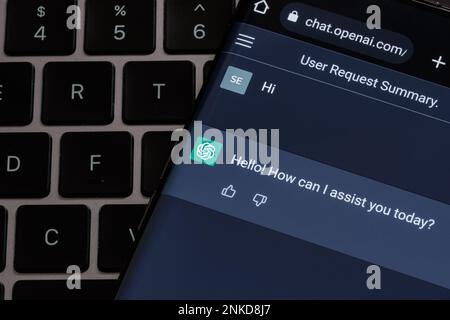 Real ChatGPT chat bot screen seen on smartphone placed on laptop keyboard. Stafford, United Kingdom, February 23, 2023 Stock Photo