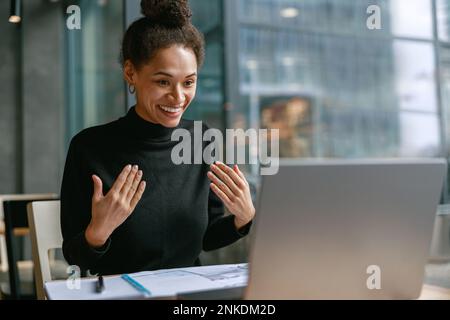 Smiling woman freelance talking with client via video call and discuss project sitting in cafe Stock Photo
