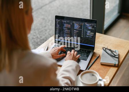 Close up of woman freelance programer working on laptop while sitting in cafe. Data done right Stock Photo