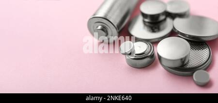 Different batteries on pink background, closeup. Banner for design Stock Photo