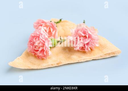 Slice of pizza with beautiful carnation flowers on light background Stock Photo