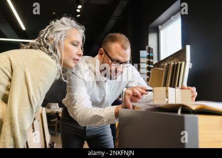 Two focused colleagues working on wooden model in architect's office together Stock Photo