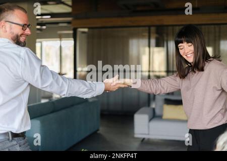 Happy businessman and woman shaking hands in office Stock Photo
