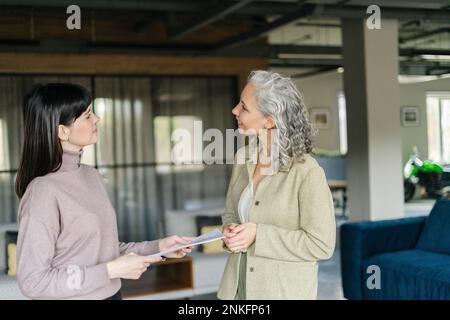 Two women with document in office facing each other Stock Photo