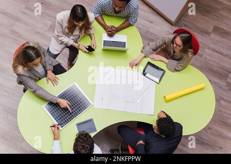 High angle view of business colleagues having a meeting with plan, wireless devices and solar panel on table Stock Photo