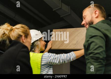 Businessman, woman and engineer examining wooden board in office Stock Photo