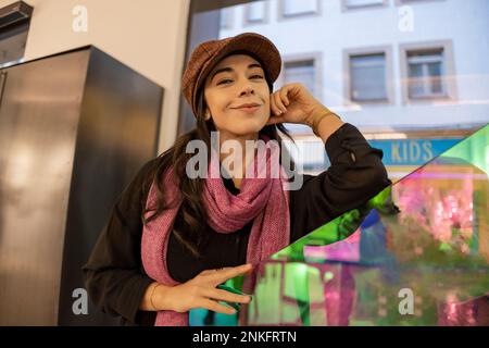 Smiling woman wearing cap standing in cafe Stock Photo