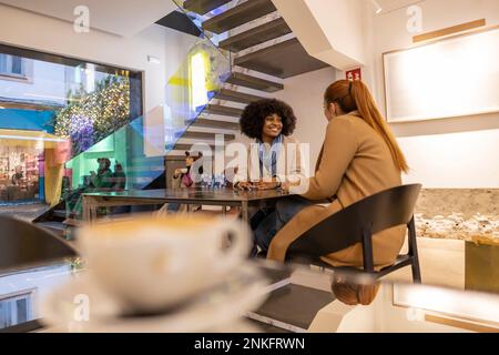 Happy friends sitting at table in cafe Stock Photo