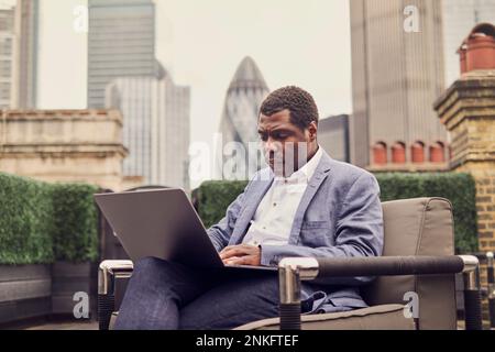Businessman working over laptop sitting on armchair Stock Photo