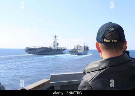 230217-N-EW498-1063 MEDITERRANEAN SEA (Feb. 17, 2023) Cmdr. Adam Stein, commanding officer of the Arleigh Burke-class guided-missile destroyer USS Delbert D. Black (DDG 119), observes the Nimitz-class aircraft carrier USS George H. W. Bush (CVN 77), left, complete an underway replenishment with the Supply-class fast combat support ship USNS Arctic (T-AOE 8). The George H.W. Bush Carrier Strike Group is on a scheduled deployment in the U.S. Naval Forces Europe area of operations, employed by U.S. Sixth Fleet to defend U.S., allied, and partner interests. (U.S. Navy photo by Lt. j.g. John P. McC Stock Photo