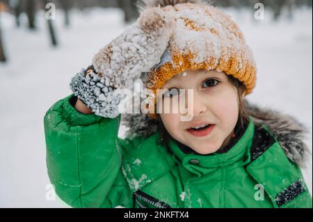 Innocent boy wearing knit hat and gloves covered in snow Stock Photo