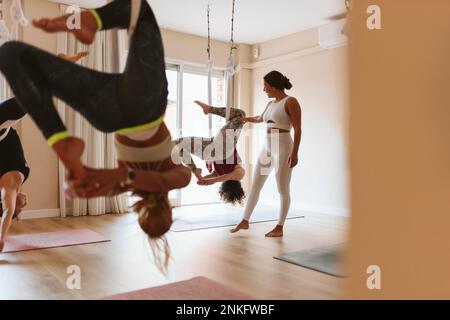 Instructor teaching aerial yoga to students in studio Stock Photo