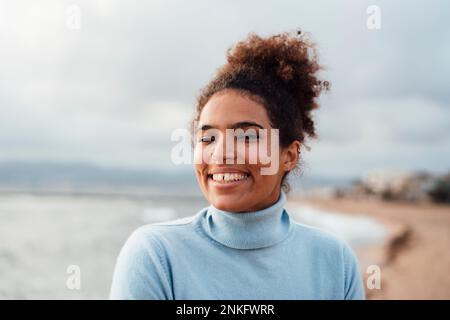 Happy young woman in Afro hairstyle at beach Stock Photo