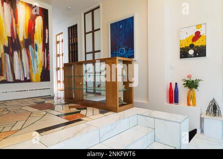 Entryway with nuanced mosaic marble steps and floor inside contemporary home decorated with paintings and sculptures. Stock Photo